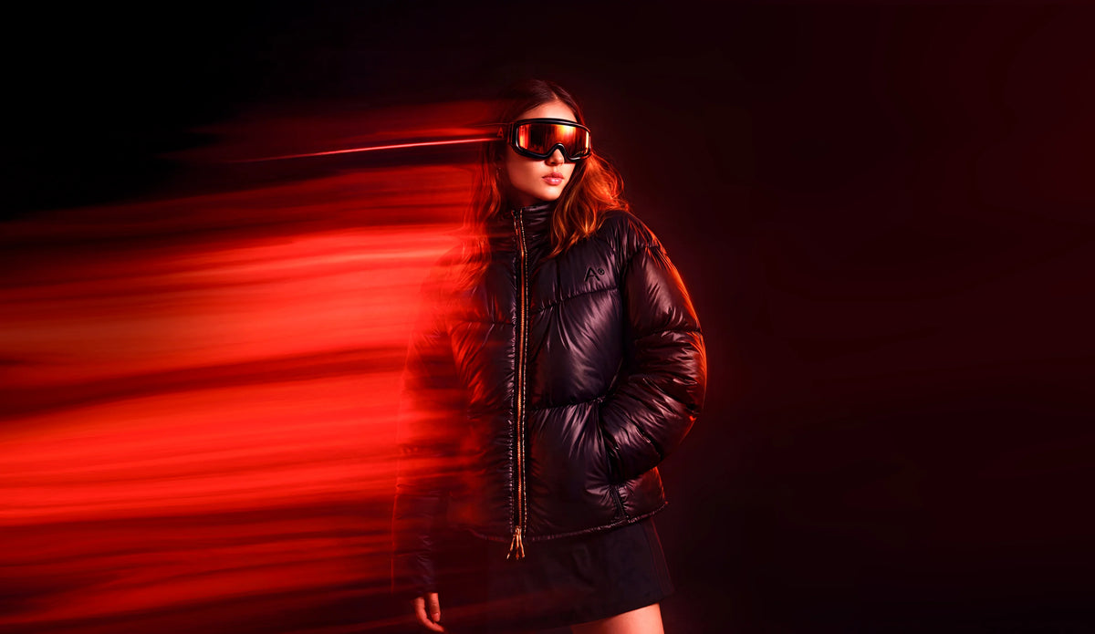 Person wearing a black jacket and goggles with a red light effect on a dark background