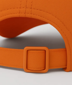 Close-up of an orange cap with a buckle on a light gray background