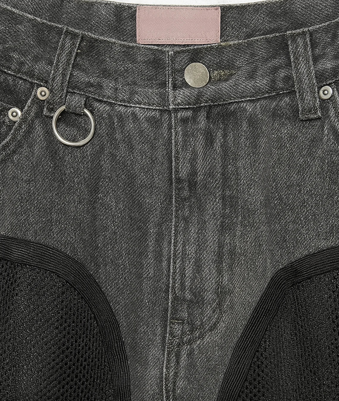 Close-up of a gray denim fabric with stitching details and a pink label.