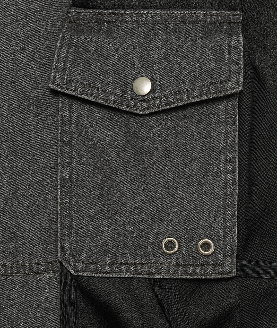Close-up of a dark gray jacket pocket with metal buttons.