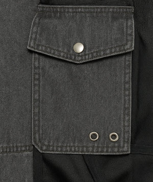 Close-up of a dark gray jacket pocket with metal buttons.
