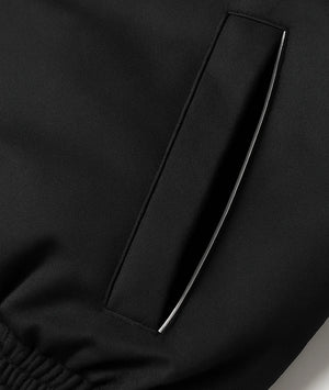Close-up of a black garment with a pocket detail on a plain background