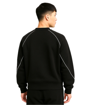 Person wearing a black tracksuit with white piping on a white background