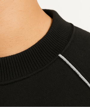 Close-up of a black garment with a white stripe on a neutral background