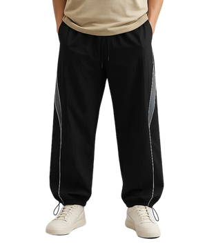 Black track pants with white stripes worn by a person on a white background