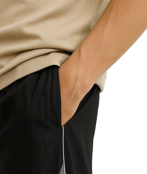 Person wearing a beige sweater and black pants with a white stripe.
