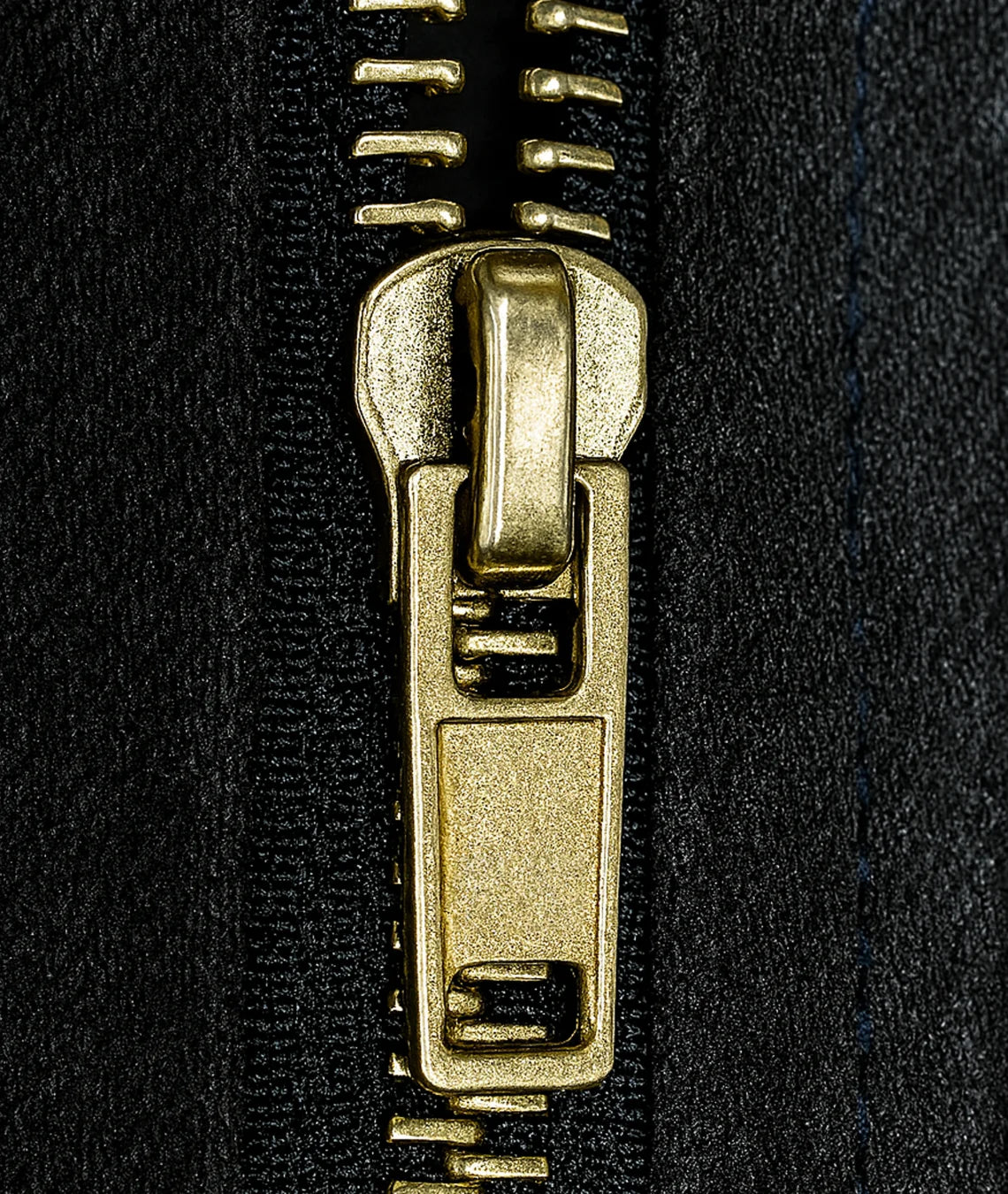 Close-up of a gold zipper pull on black fabric