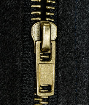 Close-up of a gold zipper pull on black fabric