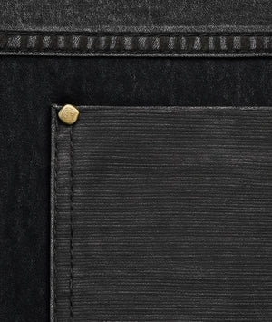 Close-up of a black leather product with a gold rivet detail
