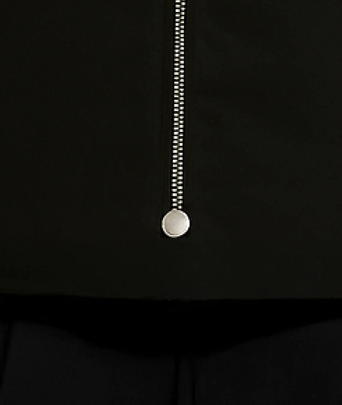 Close-up of a zipper on a black garment with a white background