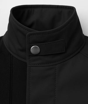Close-up of a black jacket collar with a button on a white background