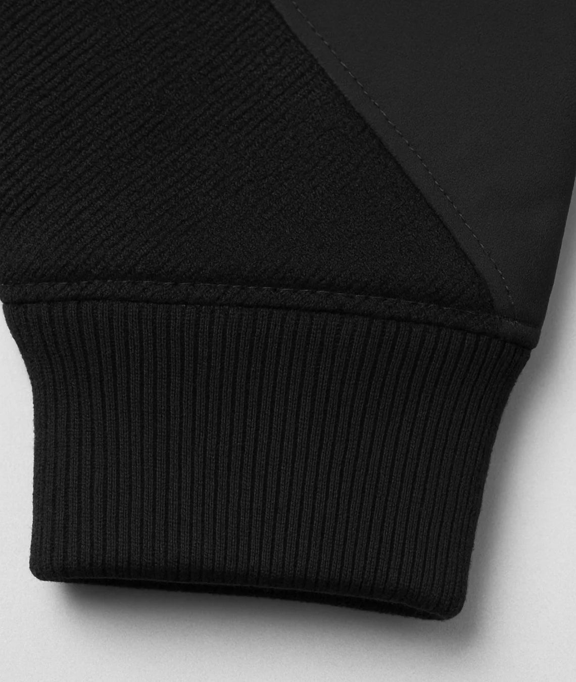 Close-up of a black sweater with ribbed cuffs on a light gray background