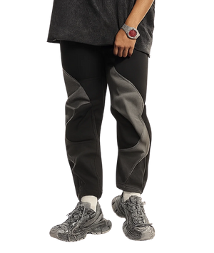 Person wearing black and gray pants with hiking shoes on a white background