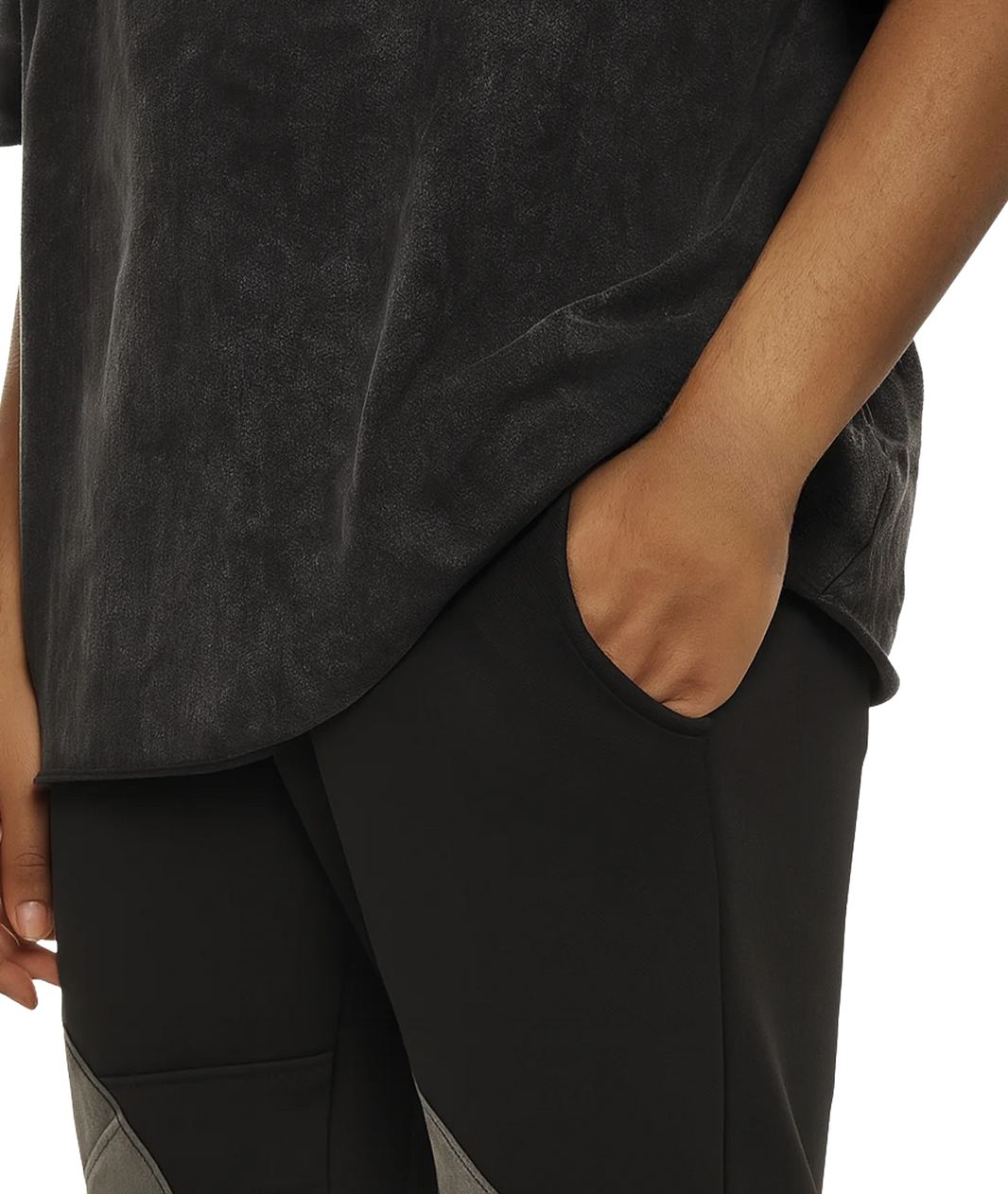 Person wearing a dark gray t-shirt and pants with one hand in a pocket on a white background