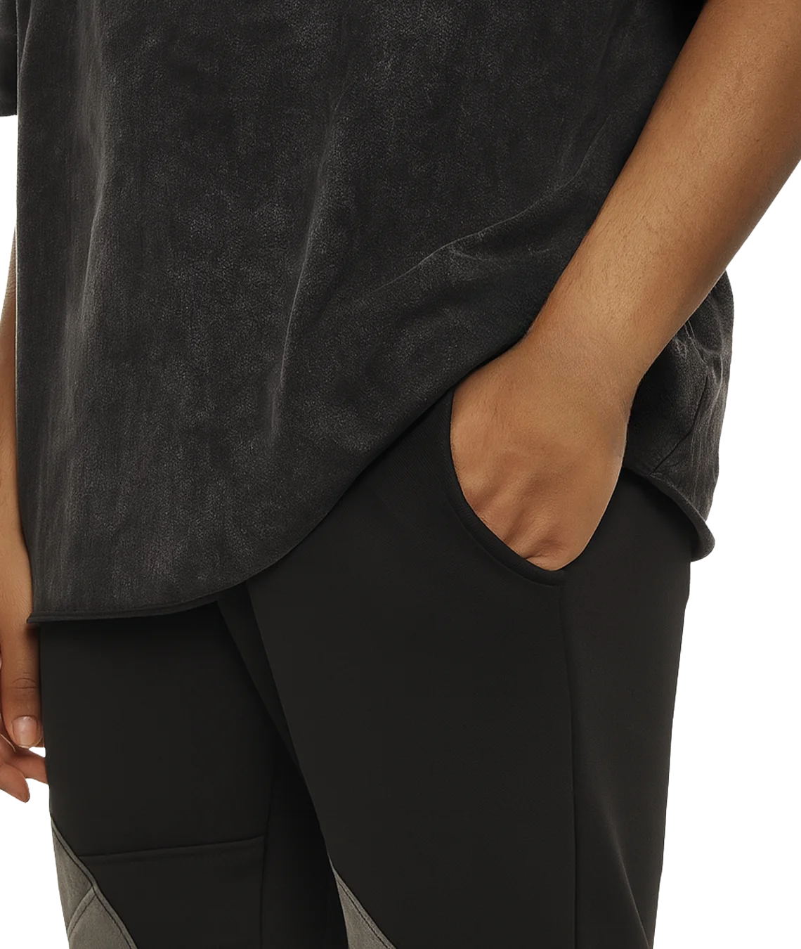 Person wearing a dark gray t-shirt and pants with one hand in a pocket on a white background