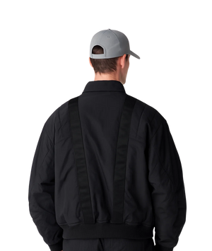 Person wearing a black jacket and gray cap from behind on a white background