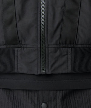 Close-up of a black jacket with a zipper and button detail.