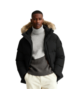 Man wearing a black puffer jacket with fur hood on a white background