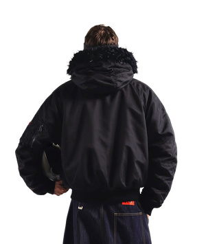 Person wearing a black jacket with fur hood on a white background
