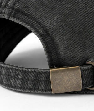 Close-up of a dark denim cap with a brass buckle on a white background