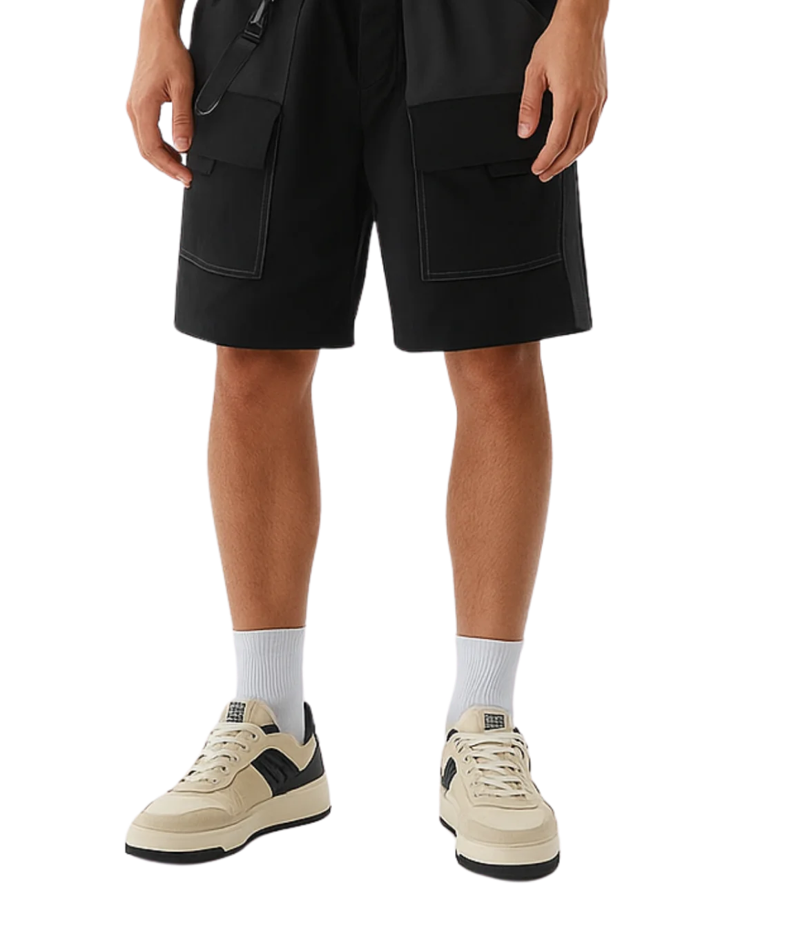 Person wearing black cargo shorts and beige sneakers on a white background
