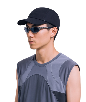 Person wearing a black cap and sunglasses with a gray sleeveless shirt on a white background
