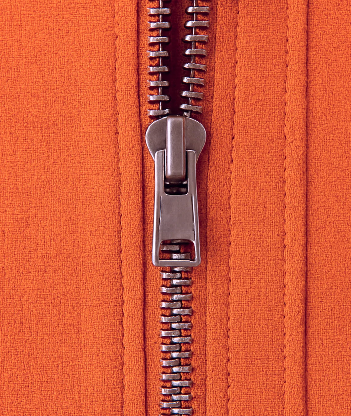 Close-up of a zipper on an orange fabric background