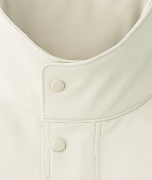 Close-up of a beige jacket with buttons on a light background