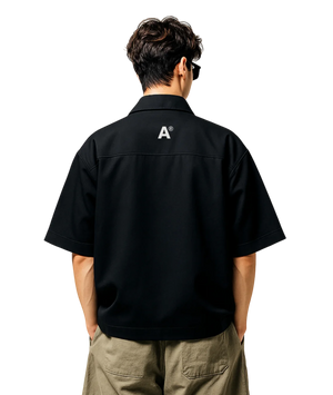 Person wearing a black shirt with a logo on the back, standing against a white background