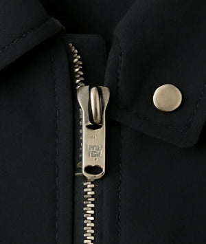 Close-up of a black coat with a zipper and button detail
