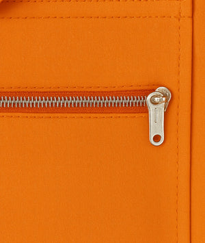 Close-up of an orange zipper on a textured surface