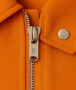 Close-up of an orange jacket with a zipper and button