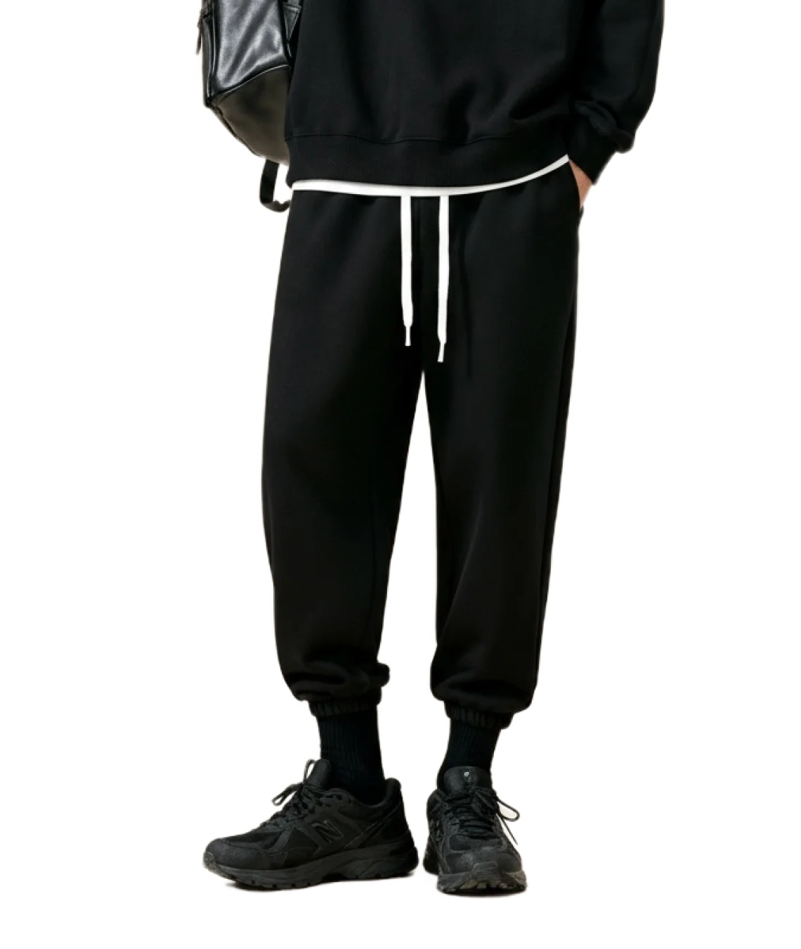 Person wearing black jogger pants with white drawstring on a white background