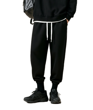Person wearing black jogger pants with white drawstring on a white background