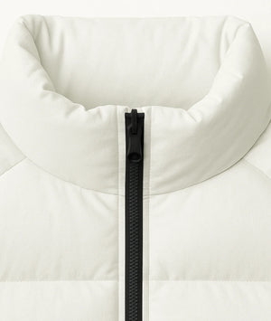 Close-up of a white puffer jacket with a black zipper on a light gray background