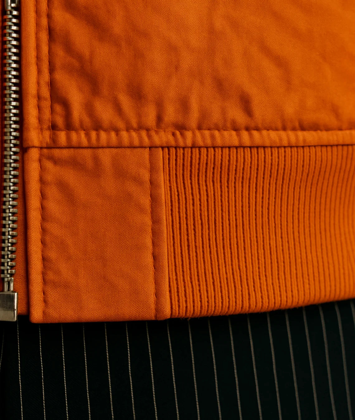 Close-up of an orange jacket with a zipper detail