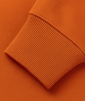 Close-up of an orange sweater sleeve on a matching background