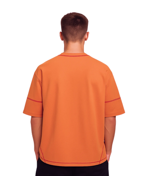 Orange polo shirt worn by a person on a white background