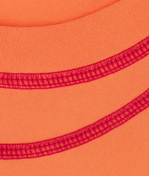 Close-up of orange fabric with red stitching detail