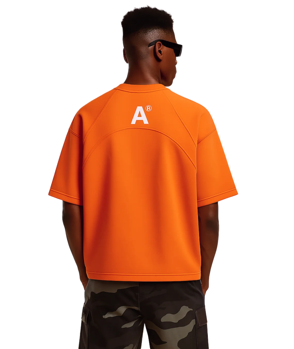 Person wearing an orange shirt with a logo on the back, standing against a white background
