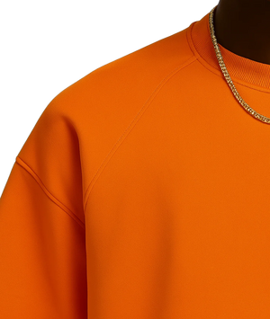 Close-up of an orange sweatshirt with a chain necklace on a white background