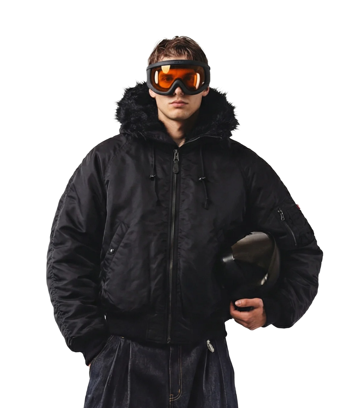 Person wearing a black winter coat and goggles holding a helmet on a white background