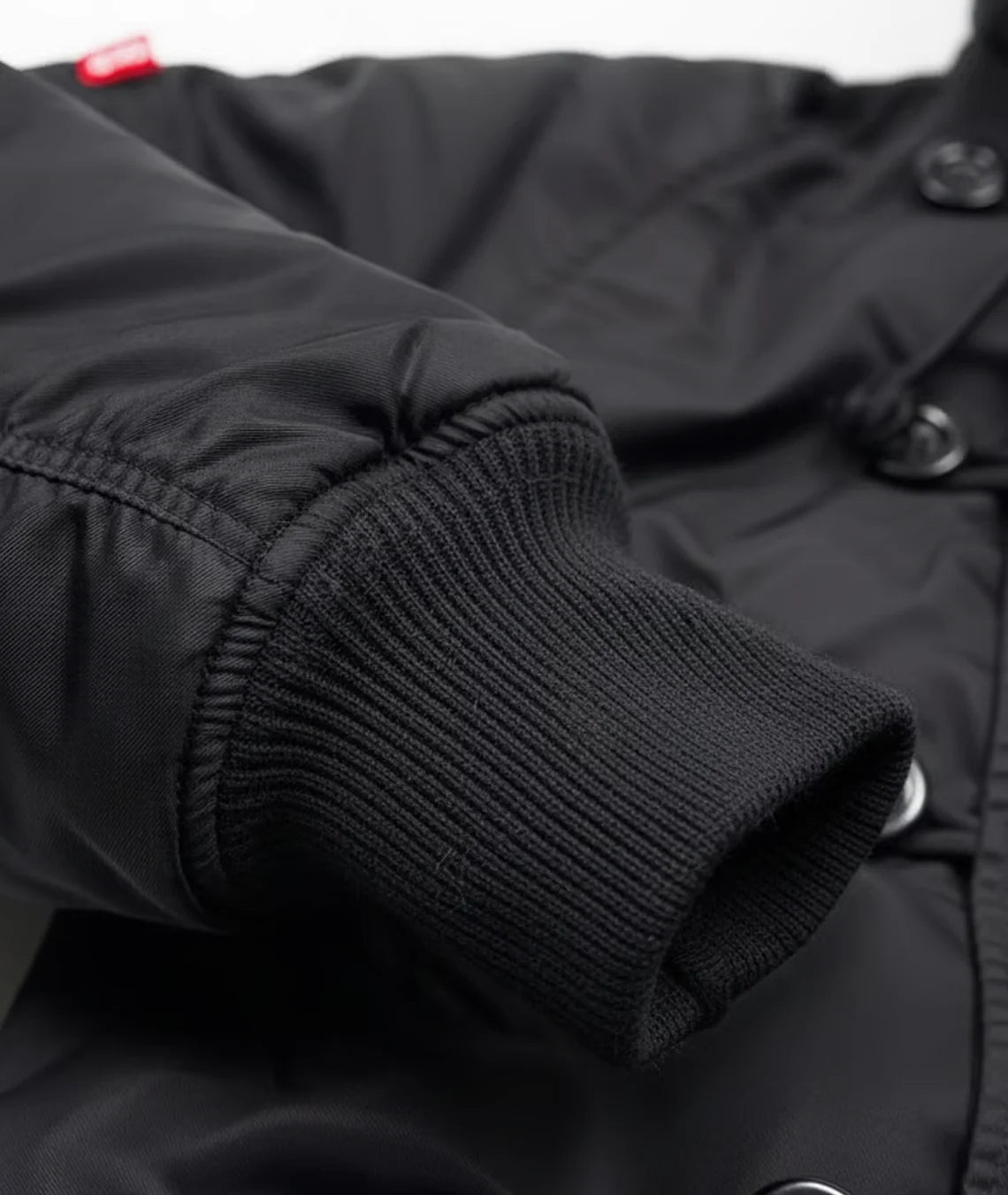 Close-up of a black jacket with knit cuffs and buttons.
