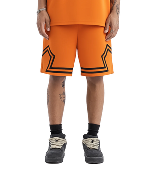 Person wearing orange shorts with black star designs on a white background