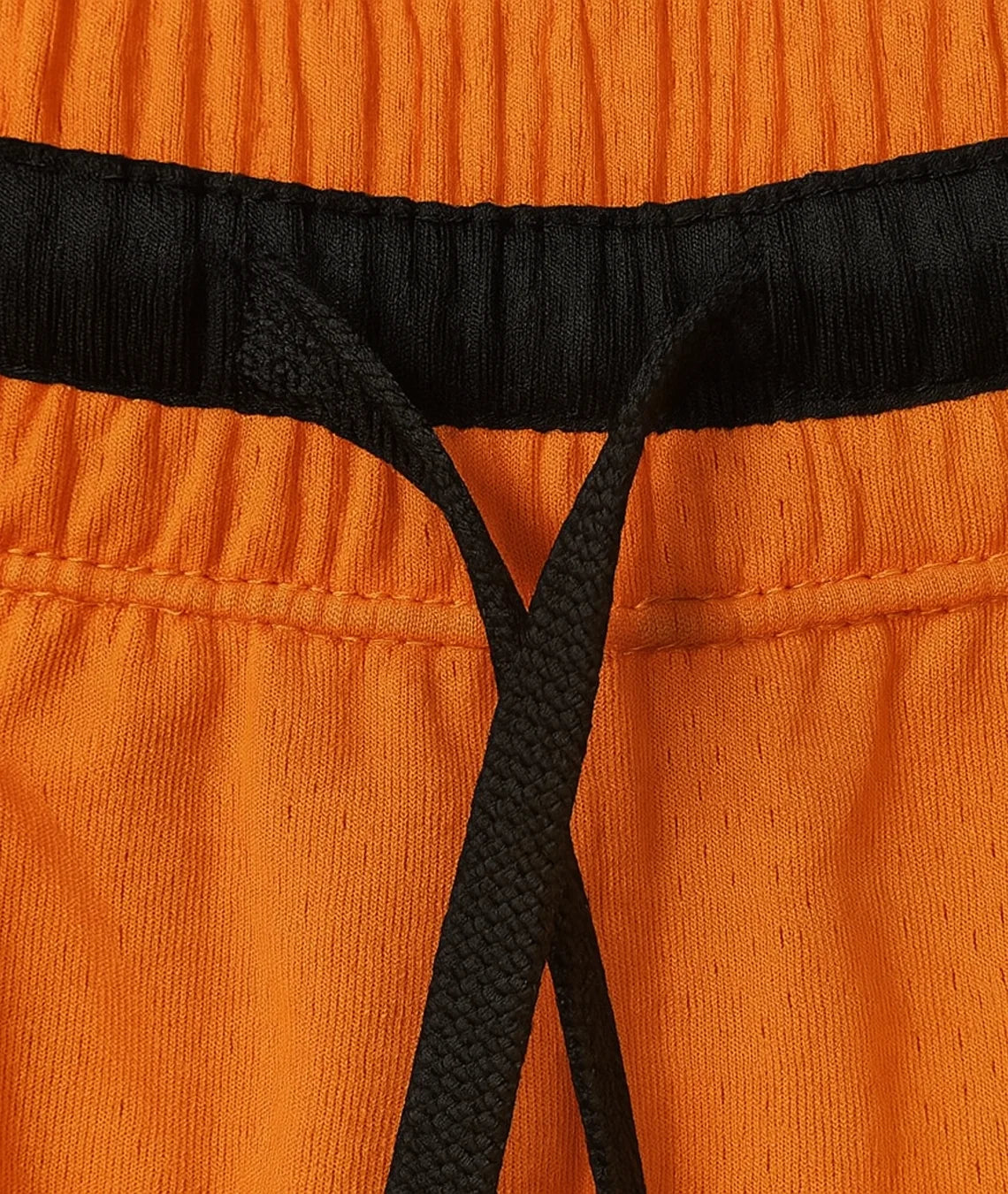 Close-up of orange pants with black waistband and drawstring