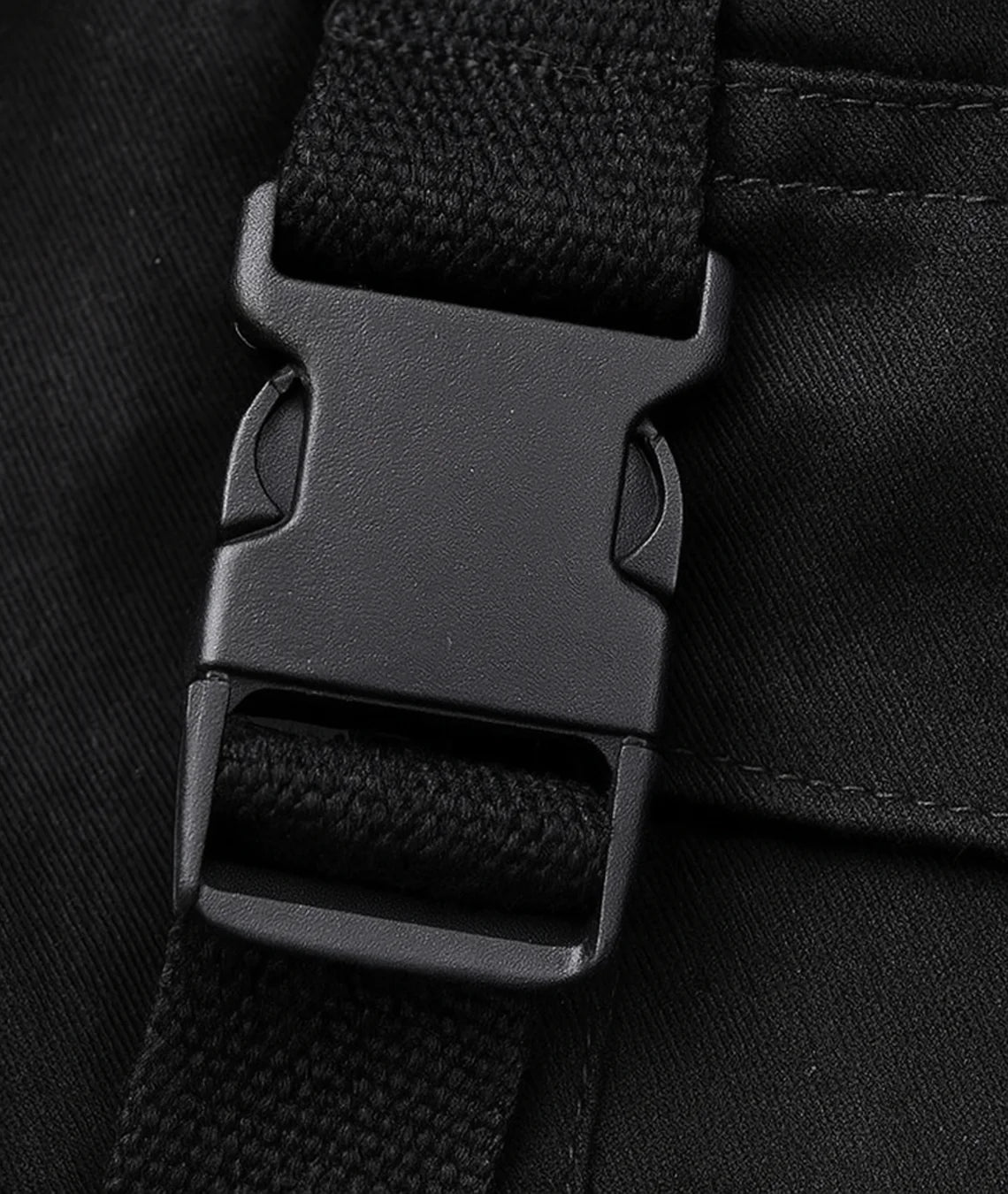 Close-up of a black backpack strap with buckle on a black background
