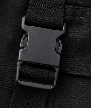 Close-up of a black backpack strap with buckle on a black background
