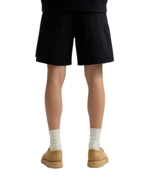Person wearing black shorts, white socks, and tan shoes on a white background