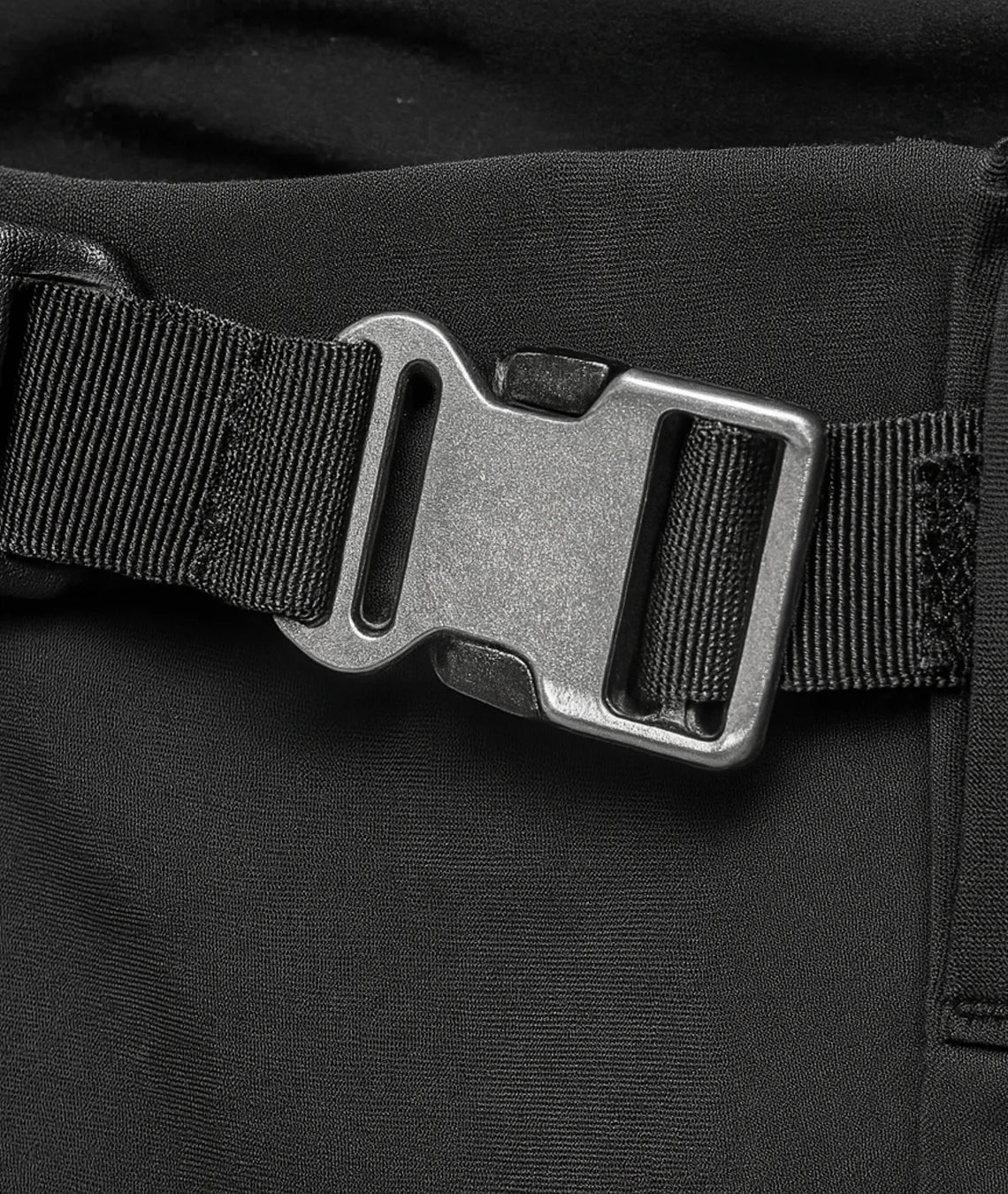 Close-up of a black belt with a metal buckle on a black background