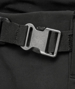 Close-up of a black belt with a metal buckle on a black background
